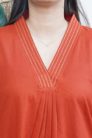 A-line Kurta with Pockets Sona Mart 3 Model wearing a solid rust-colored A-line kurta with V-neck embroidery and side pockets, paired with black pants.