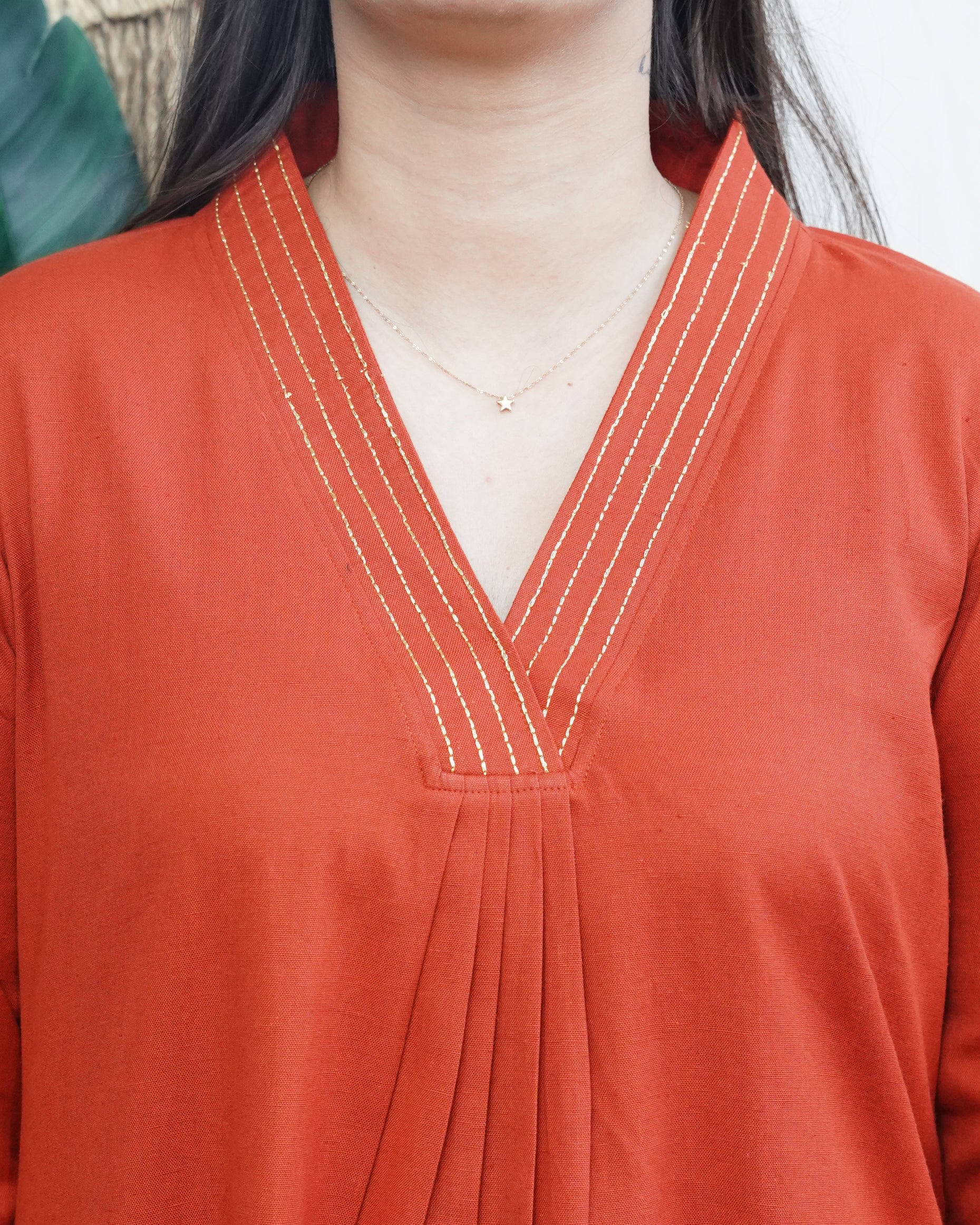 A-line Kurta with Pockets Sona Mart2 Model wearing a solid rust-colored A-line kurta with V-neck embroidery and side pockets, paired with black pants.