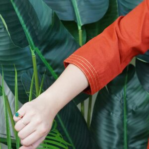 Model wearing a solid rust-colored A-line kurta with V-neck embroidery and side pockets, paired with black pants.