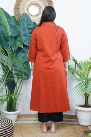 A-line Kurta with Pockets Sona Mart 5 Model wearing a solid rust-colored A-line kurta with V-neck embroidery and side pockets, paired with black pants.