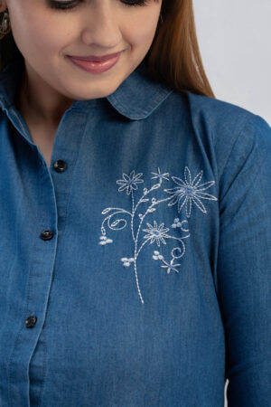 Close up of floral embroidery and collar on blue denim shirt dress
