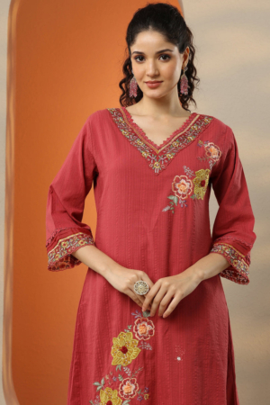 Close up of V-neckline, lace trims, and floral embroidery on a pink kurta.