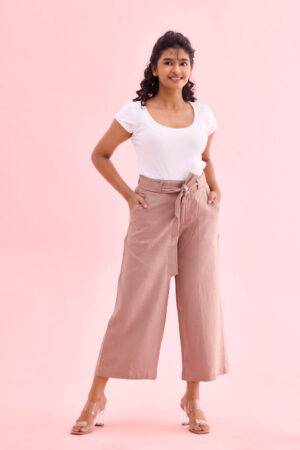 Close up of high-rise elasticated waistband with fabric tie-belt on beige culottes.